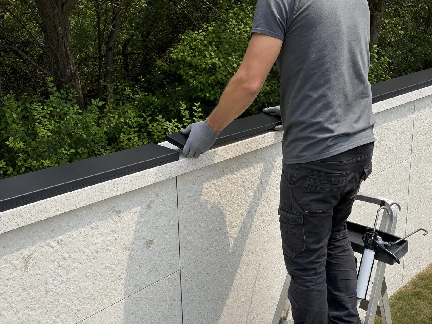 Installer placing a matte-black wall-top sensor onto the prepared perimeter wall surface